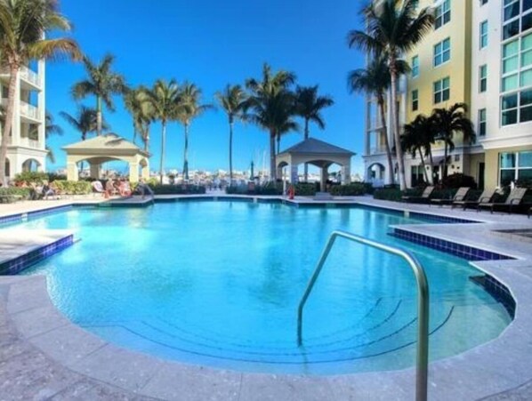 Relax by the pool surrounded by palm trees and lounge chairs.