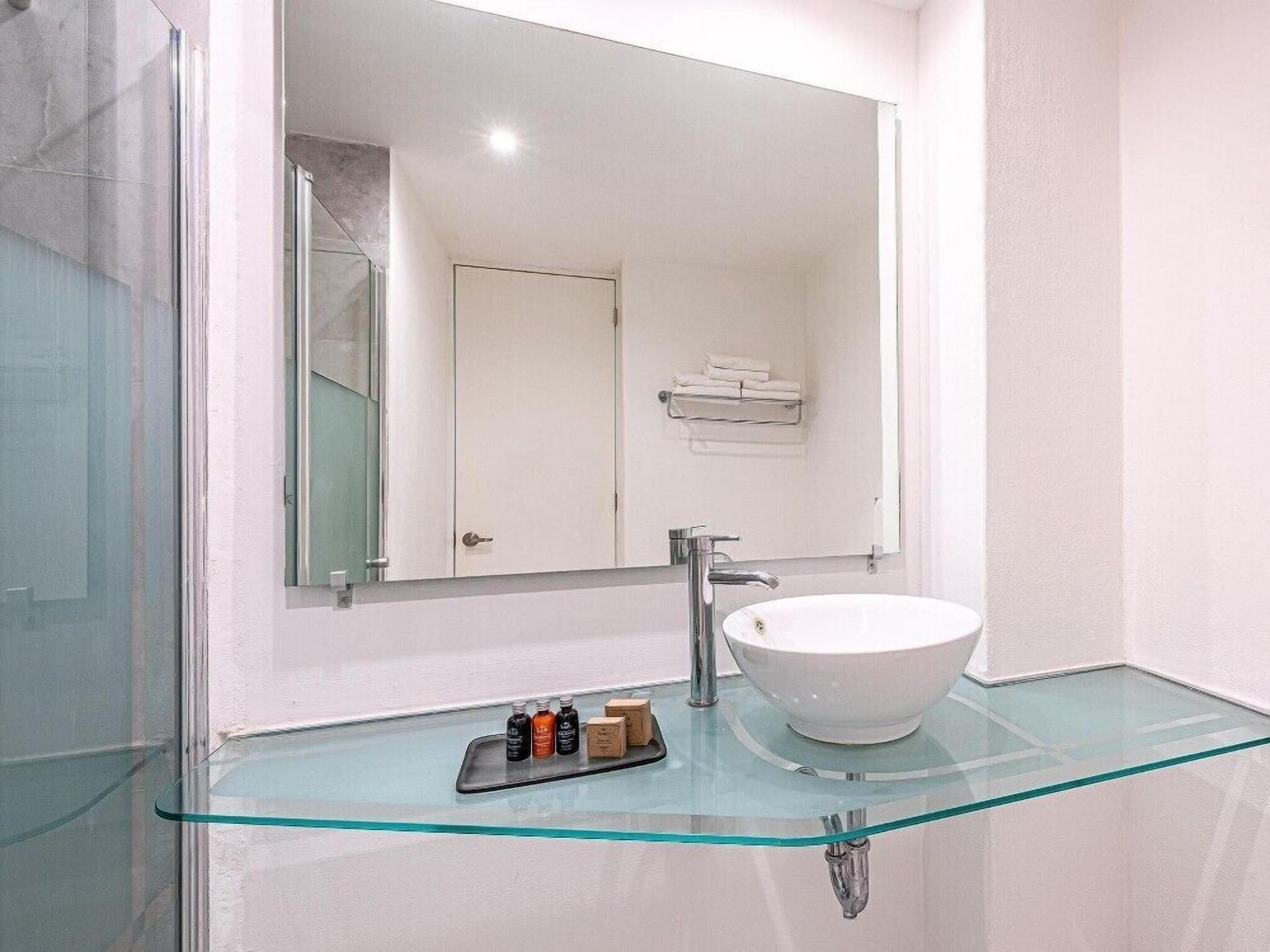 A modern bathroom with a glass sink, a chrome faucet, and a glass shower enclosure.