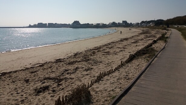 A sandy beach with a wooden boardwalk, a clear sky, and buildings in the distance. - Studio Vue mer RDC à 100 m de la Plage (Larmor-Plage)