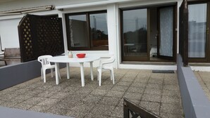 A patio with a white table and chairs, a red bowl, and a vase. - Studio Vue mer RDC à 100 m de la Plage (Larmor-Plage)