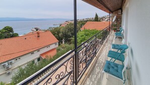 Un balcon donnant sur la mer, des toits couverts de tuiles rouges et un mur en pierre.