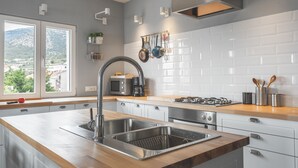 Une cuisine moderne dotée d’un grand îlot central, d’appareils électroménagers en acier inoxydable et offrant une vue sur l’extérieur.