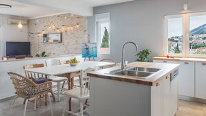 Une cuisine moderne dotée d’un îlot central, de meubles blancs et d’une grande fenêtre donnant sur la ville.