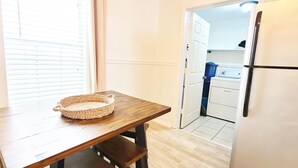Une petite cuisine avec une table en bois, un panier en osier et un réfrigérateur blanc.
