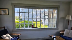 Une pièce avec une grande fenêtre, un banc en bois, un canapé bleu et une petite table.
