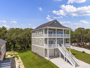 A two-story building with a balcony on the upper floor, a covered front porch, and a staircase leading to the entrance.