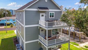 Een tweelaags huis met een balkon op de bovenverdieping, een klein voortuintje en een zichtbare airconditioning.