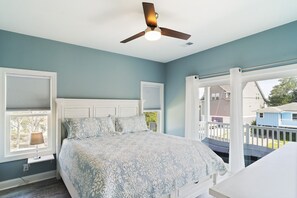 A bedroom with a bed, a ceiling fan, and a view of the outside.