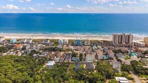 Een kustwoongebied met een strand, huizen en een groot hotelgebouw.