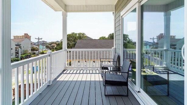 A covered porch with a white railing, a ceiling fan, and two metal chairs. - Beautiful Home, Ocean Views, Block from Ocean, within 5mi of 7 Golf Courses,   (North Myrtle Beach)