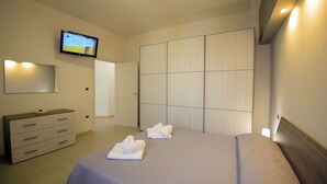 A hotel room with a bed, a TV mounted on the wall, a wardrobe, and a bedside table. - Casa A&F - Fra (Torricella)