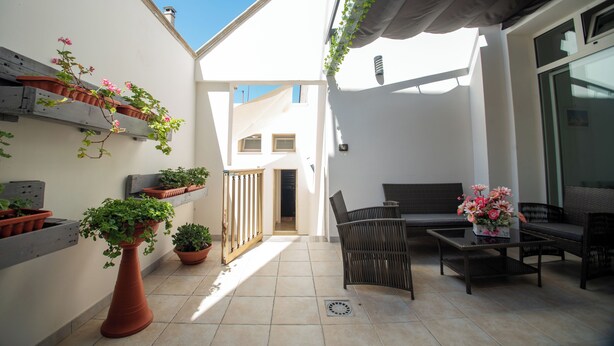 A patio area with potted plants, a seating arrangement, and a view of the interior. - Casa A&F - Fra (Torricella)