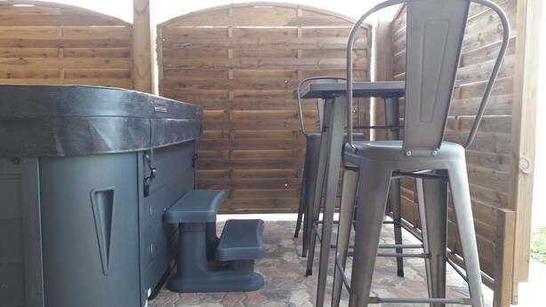 Un'area patio con una griglia barbecue, due sgabelli da bar e un piccolo sgabellino.