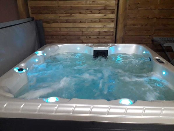 A hot tub with multiple jets, set against a wooden wall.