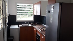 Una cucina compatta con frigorifero, fornello, lavello e mobili.