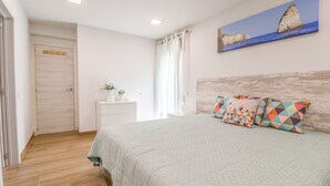 A bedroom with a bed, a nightstand, a painting, and a wooden headboard.