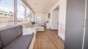 A modern living room with a grey sofa, a white armchair, and a wooden floor.