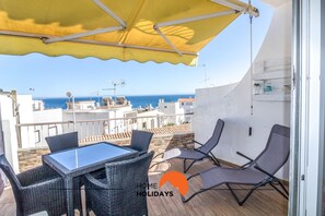 Un balcon avec une table et des chaises, offrant une vue sur la côte.