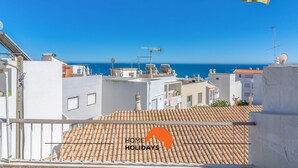 A rooftop terrace with a view of the sea, featuring a tiled roof and a yellow umbrella. - #057 T1 Rossio 43D by Home Holidays (Albufeira)