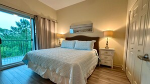 A bedroom with a large bed, a nightstand, a lamp, a ceiling fan, and a sliding glass door to a balcony. - Beach Retreat in Perdido Key, Florida (Pensacola)