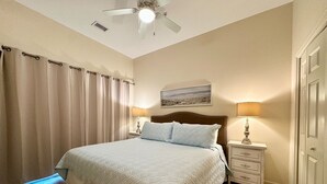 A bedroom with a bed, nightstands, a ceiling fan, and a painting on the wall. - Beach Retreat in Perdido Key, Florida (Pensacola)