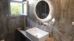 A bathroom with a large oval mirror, a window, and a sink. - Orea Superior Rooms (Zakynthos)