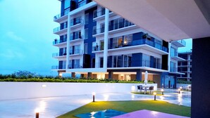 Een modern hotel met meerdere verdiepingen, balkons, buiten zitplaatsen en een goed verlichte binnenplaats.
