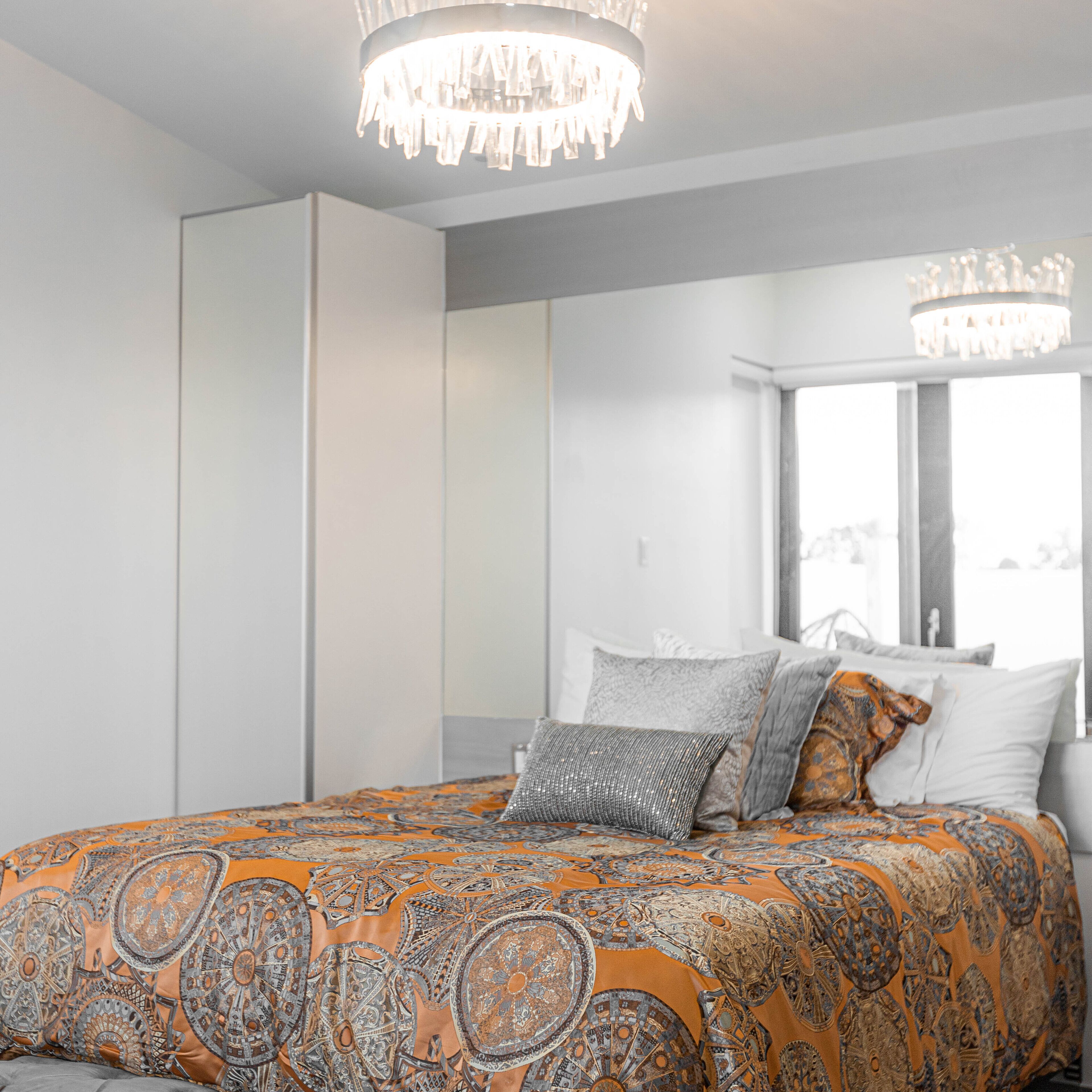 Ein Schlafzimmer mit einem großen Bett, einer Chandelüster und einem Fenster mit Blick.