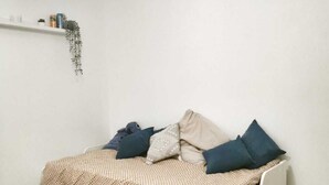 A single-bed room with a white bed, beige and patterned bedding, and a small rug. - Villa swimming pool barbecue terrace in the heart of Provence (Neoules)