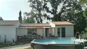 An outdoor swimming pool with a pergola and patio furniture, surrounded by a garden and a house with a tiled roof. - Villa swimming pool barbecue terrace in the heart of Provence (Neoules)