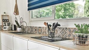 A modern kitchen with white cabinets, a striped window blind, and a view of greenery outside. - Villa swimming pool barbecue terrace in the heart of Provence (Neoules)