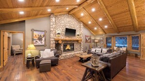 Un salon spacieux avec une cheminée en pierre, un plafond en bois et de grandes fenêtres.