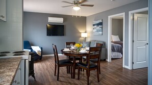 A modern kitchen with a dining area, a ceiling fan, and a flat-screen TV mounted on the wall. - Great Blue Resorts - Golden Beach Resort (Alnwick/Haldimand)