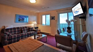 Een woonkamer met een bank, salontafel, televisie en een balkon met uitzicht.