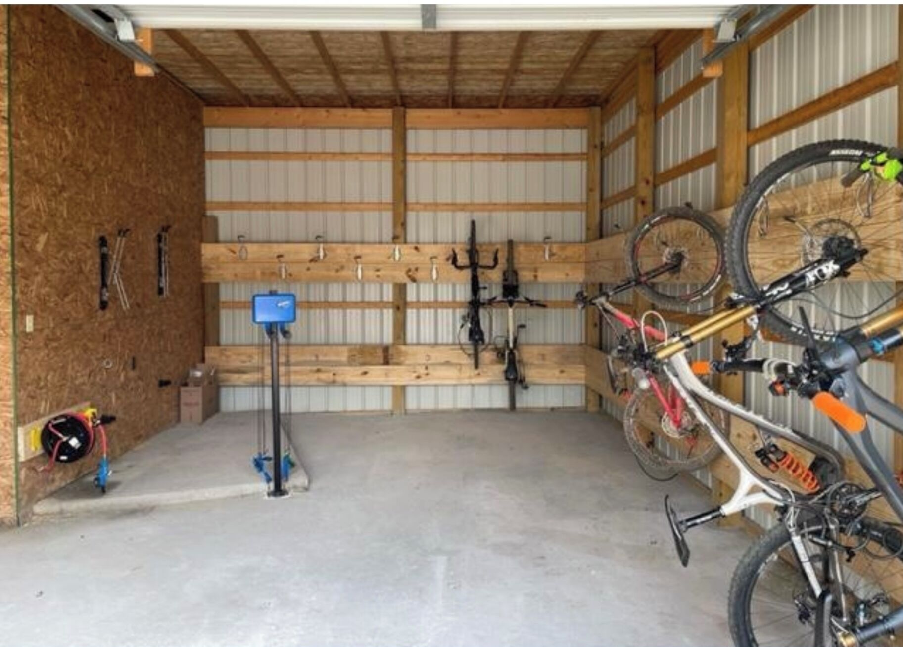 Un espacio interior techado con suelo de hormigón, paredes de madera y revestimiento de metal.