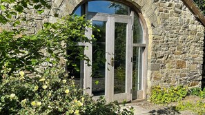 A stone building with a large arched window and a wooden door. - Crug Yr Eryr Isaf (Llandysul)
