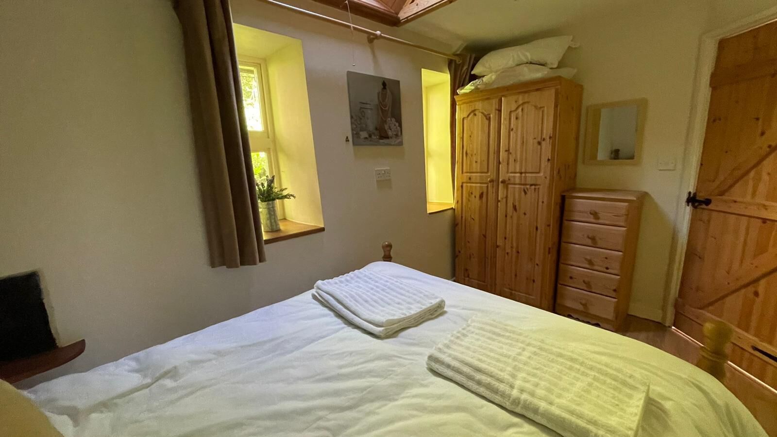 A bedroom with a bed, a wardrobe, and a window.