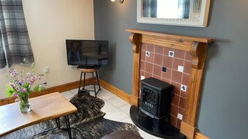 Una sala de estar acogedora con chimenea, televisor y una mesa de comedor con un jarrón de flores.