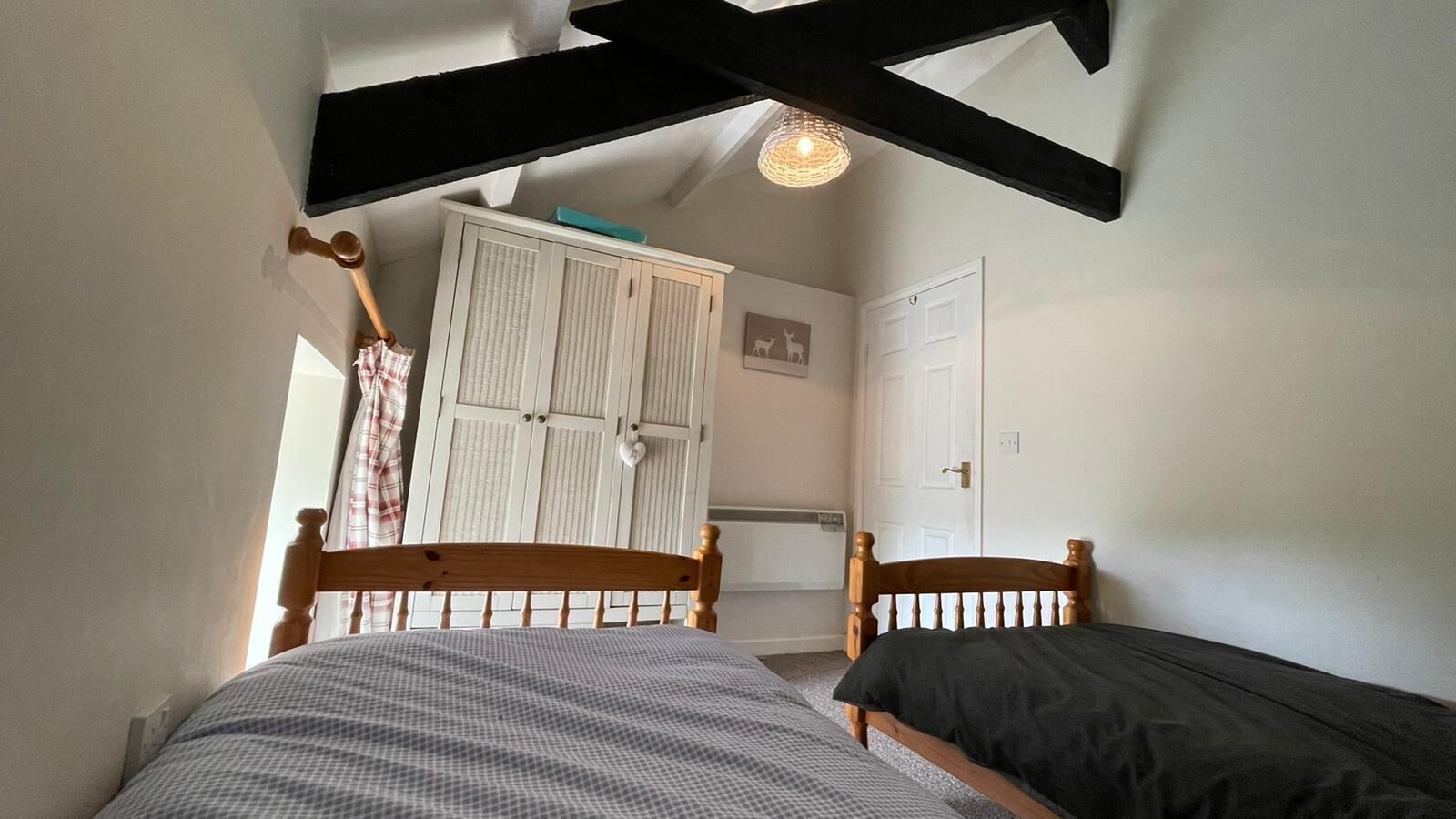 Une chambre avec deux lits simples, une armoire, un radiateur et un luminaire au plafond.