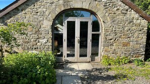 A stone building with a large arched entrance and a glass door. - Crug Yr Eryr Isaf (Llandysul)