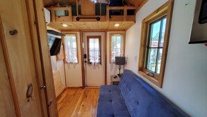 Une pièce chaleureuse avec un plafond en bois, un canapé bleu et un téléviseur fixé au mur.