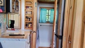 Une cuisine compacte pour camping-car, dotée de meubles en bois, d’un four à micro-ondes intégré et d’une petite fenêtre avec des rideaux.