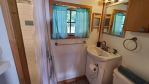 Une salle de bain avec un lavabo blanc, un miroir, un porte-serviette et des toilettes.