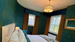 A hotel room with a bed, a nightstand, a lamp, and a window with curtains. - Old Spittal Hospital Apartment (Stirling)