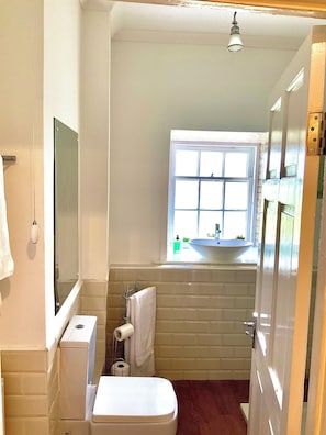A compact bathroom with a toilet, sink, and window. - Old Spittal Hospital Apartment (Stirling)