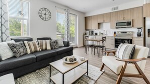 A modern living room with a sofa, coffee table, and a dining area with chairs. - Downtown Modern Bungalow (Dallas)
