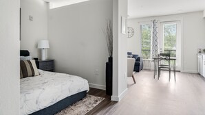 A modern bedroom with a bed, bedside table, lamp, and a tall vase. - Downtown Modern Bungalow (Dallas)
