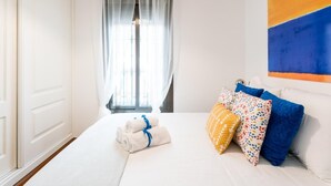 Ett hotellrum med en säng, ett fönster med tunna gardiner och en tavla på väggen.