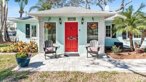 A house with a red door, two chairs outside, and a sign that says "WELCOME".