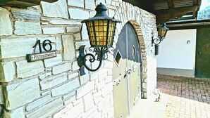 A stone wall with a street sign reading "Pfaffenstewadt" and two wall-mounted lanterns. - Exclusive Villa Tirol (Fieberbrunn)